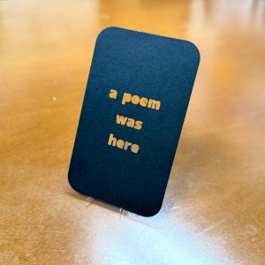Black card with words "a poem was here" cutout.